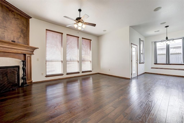 unfurnished living room with dark wood-style floors, visible vents, a healthy amount of sunlight, and ceiling fan with notable chandelier