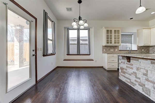 unfurnished dining area with dark wood-style flooring, visible vents, and an inviting chandelier
