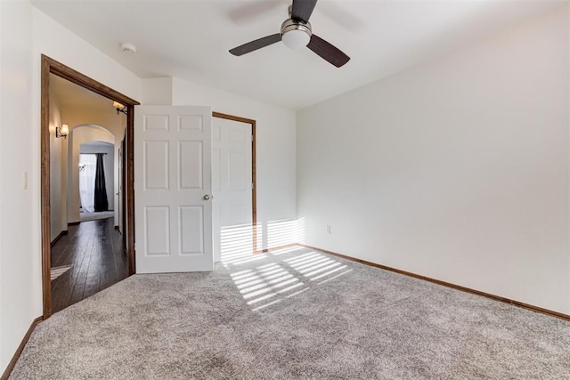 unfurnished bedroom featuring arched walkways, carpet, baseboards, and ceiling fan