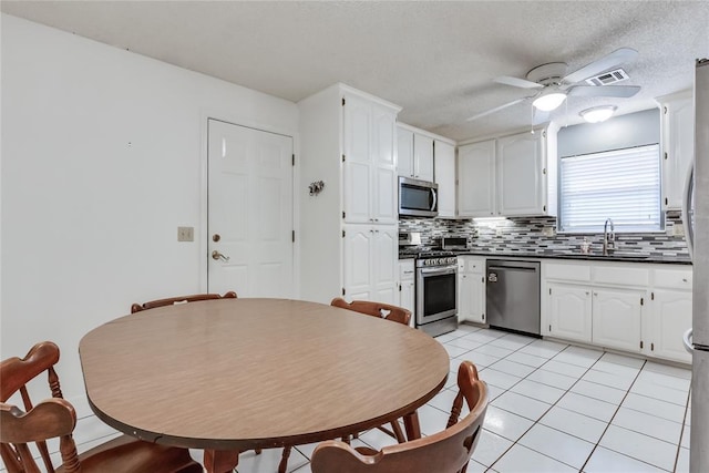 7205 N Seminole Ter, Warr Acres, OK 73132 - kitchen with dark countertops, decorative backsplash, stainless steel appliances, a sink, and ceiling fan