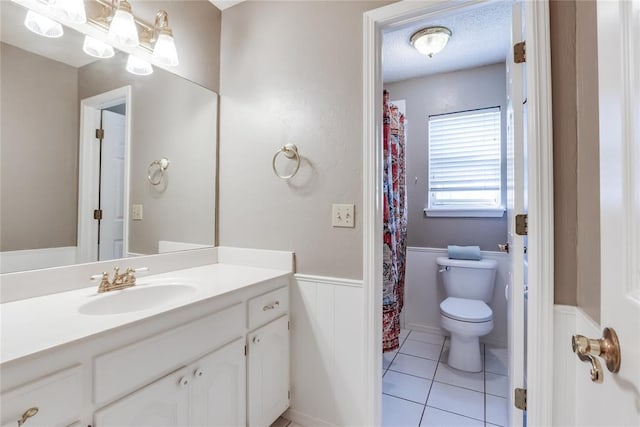 7205 N Seminole Ter, Warr Acres, OK 73132 - full bathroom featuring vanity, tile patterned flooring, a textured ceiling, toilet, and a wainscoted wall