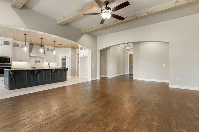 4174 Richards Way, Piedmont, OK 73078 - unfurnished living room featuring beamed ceiling, arched walkways, ceiling fan, light wood-style flooring, and a chandelier