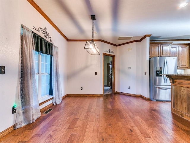 407 Heather Ln, Tuttle, OK 73089 - kitchen featuring stainless steel fridge, crown molding, wood-type flooring, baseboards, and hanging light fixtures