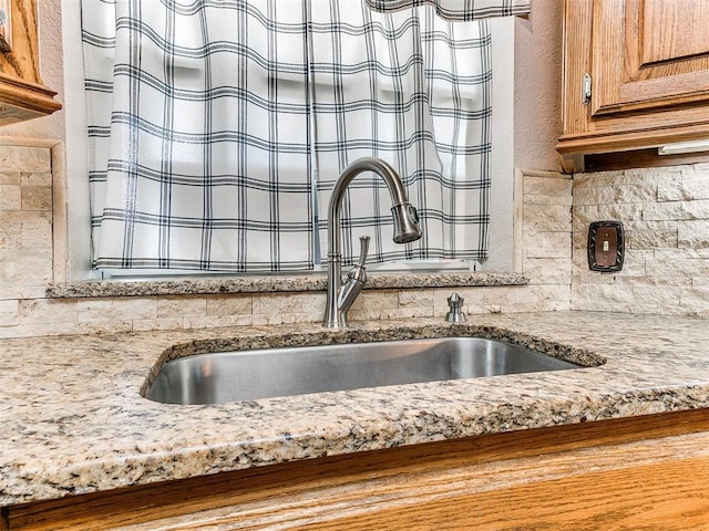407 Heather Ln, Tuttle, OK 73089 - kitchen view of a sink, brown cabinetry, backsplash, and light stone countertops