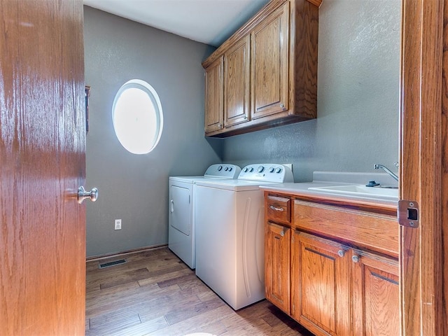 407 Heather Ln, Tuttle, OK 73089 - laundry area with separate washer and dryer, cabinet space, light wood-type flooring, and a textured wall