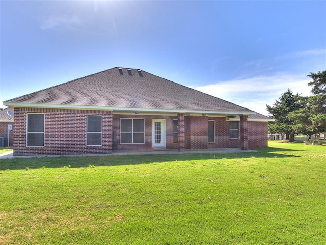 407 Heather Ln, Tuttle, OK 73089 - rear view of house featuring a lawn, roof with shingles, brick siding, central air condition unit, and a patio area