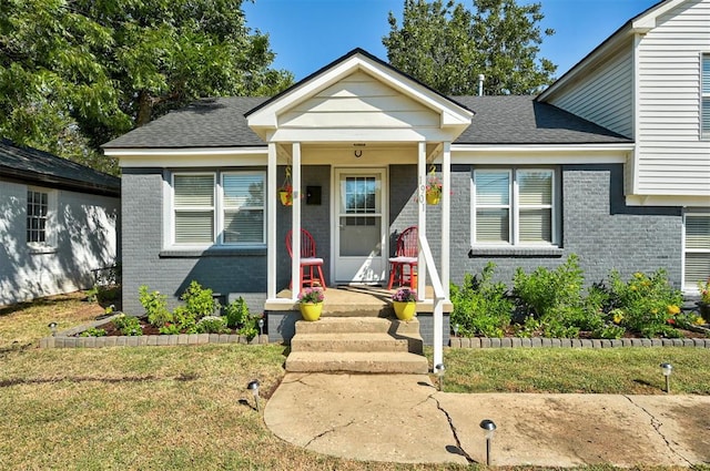 view of front of property with roof with shingles, covered porch, and brick siding