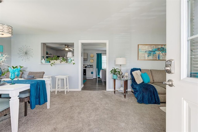 carpeted living room with baseboards and a ceiling fan