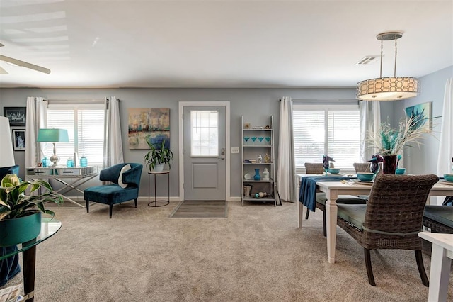 dining room with light carpet, a ceiling fan, and a healthy amount of sunlight
