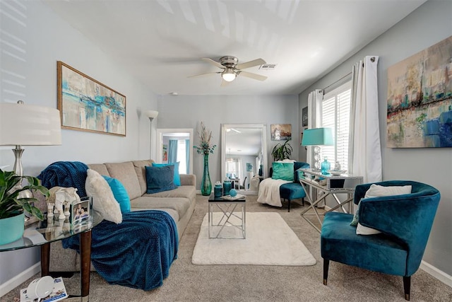 living room with visible vents, carpet floors, baseboards, and ceiling fan