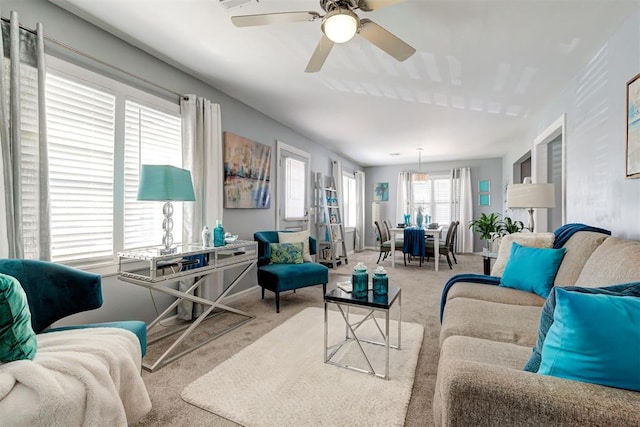 carpeted living room featuring baseboards and a ceiling fan