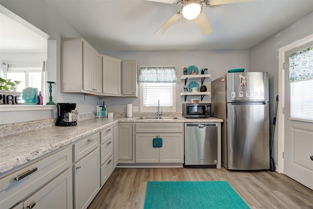 kitchen featuring light wood-style floors, ceiling fan, a sink, and appliances with stainless steel finishes
