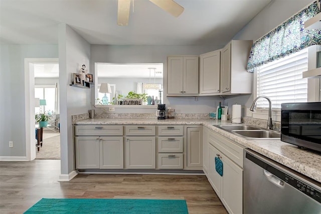 kitchen featuring light countertops, light wood-style floors, ceiling fan, dishwasher, and a sink