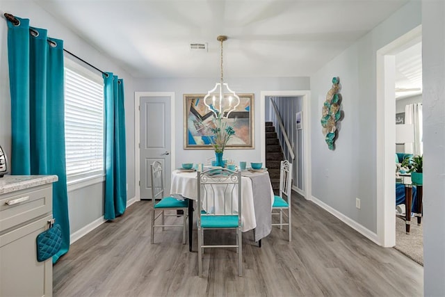 dining room with baseboards, light wood-type flooring, a notable chandelier, and stairs