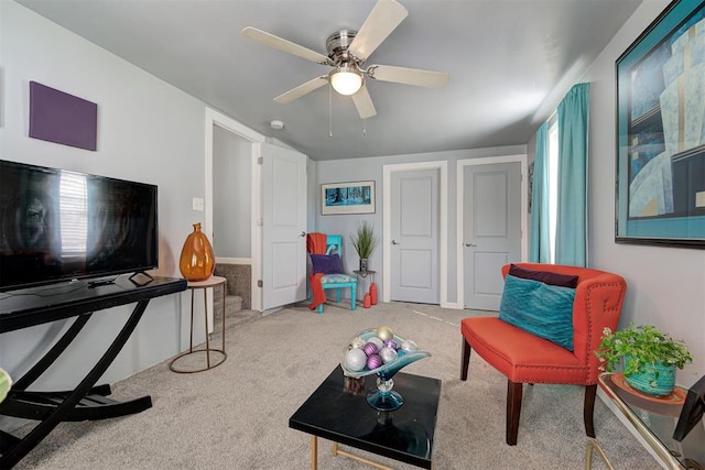 living area with a ceiling fan and carpet