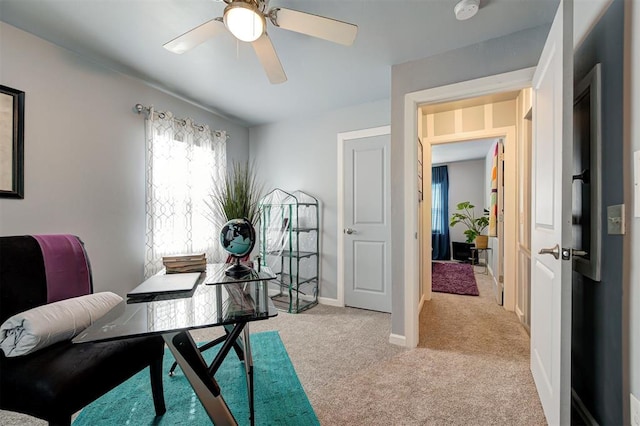 office space with baseboards, a ceiling fan, and light carpet