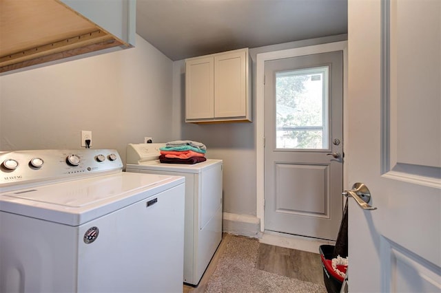 laundry area featuring light wood finished floors, washing machine and dryer, and cabinet space