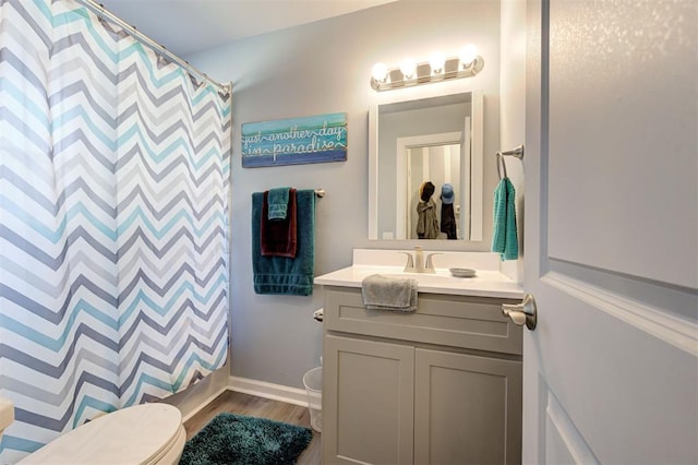 bathroom featuring vanity, baseboards, a shower with curtain, toilet, and wood finished floors