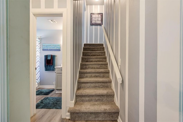 stairway featuring wood finished floors and visible vents