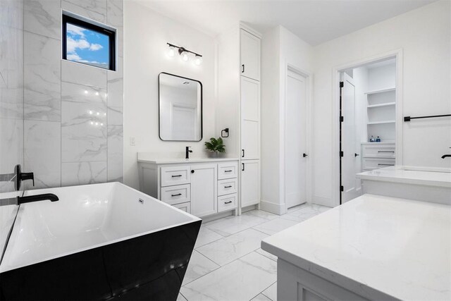 2109 Wiregrass Rd, Edmond, OK 73025 - bathroom with marble finish flooring, vanity, a soaking tub, and a closet