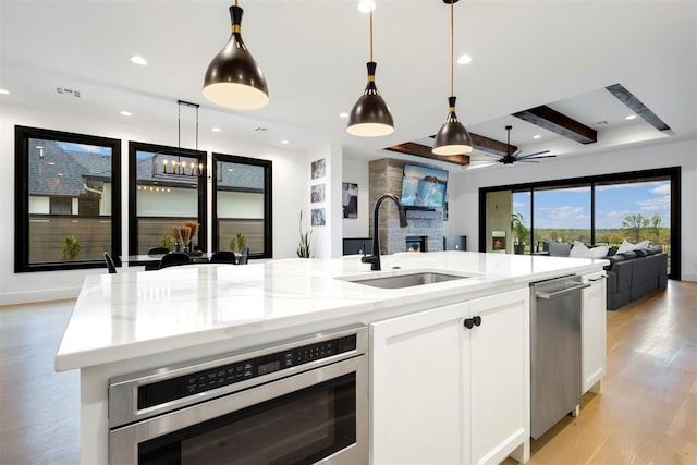2109 Wiregrass Rd, Edmond, OK 73025 - kitchen featuring open floor plan, wall oven, stainless steel dishwasher, light stone counters, and decorative light fixtures