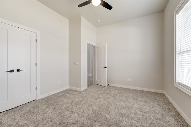 unfurnished bedroom featuring light carpet, multiple windows, and baseboards