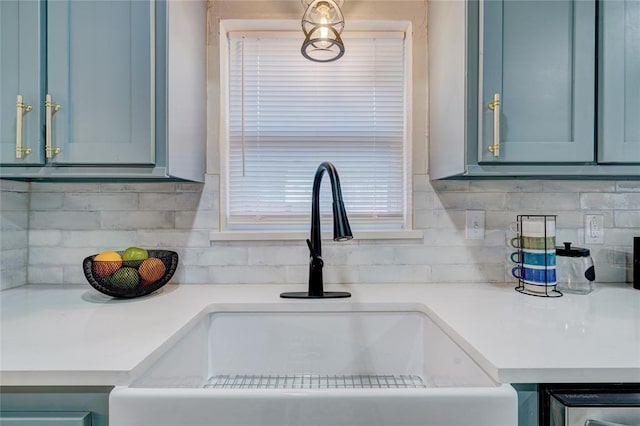 2765 NW 20th St, Oklahoma City, OK 73107 - kitchen featuring light countertops, a sink, blue cabinets, and decorative backsplash