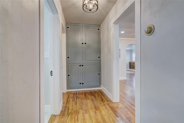 2765 NW 20th St, Oklahoma City, OK 73107 - hall featuring baseboards, light wood-type flooring, arched walkways, and an inviting chandelier