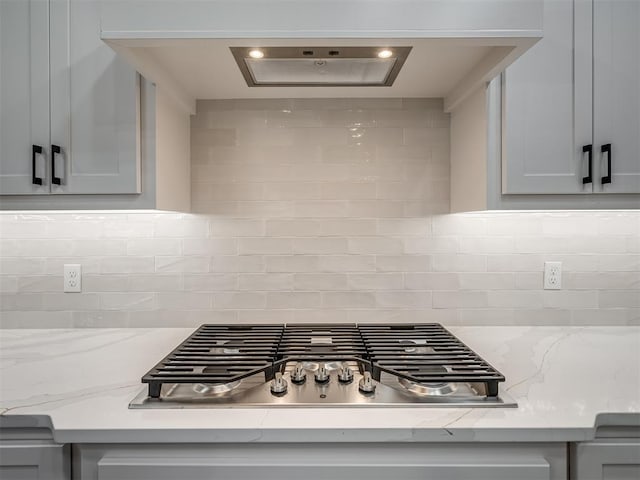 15216 Bedford Rd, Edmond, OK 73013 - details featuring gray cabinets, stainless steel gas stovetop, tasteful backsplash, and light stone countertops
