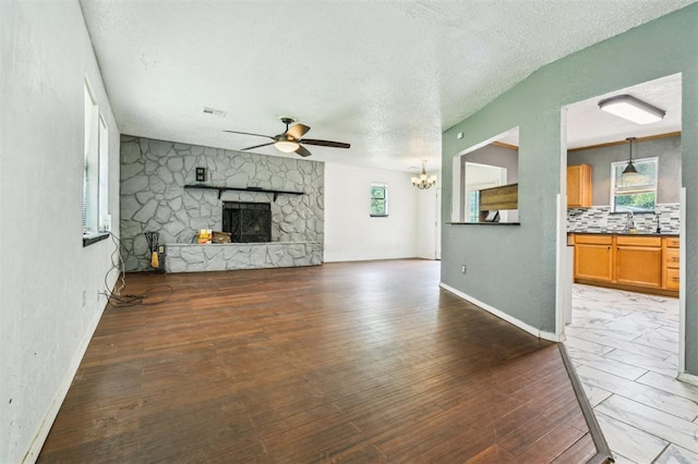 3206 Oakbriar Dr, Choctaw, OK 73020 - unfurnished living room with ceiling fan, a fireplace, wood finished floors, baseboards, and a textured ceiling