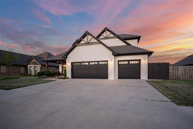 view of front of home featuring driveway, fence, an attached garage, a shingled roof, and stucco siding