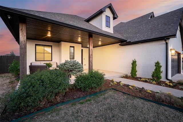 view of front of home with brick siding, a porch, and fence