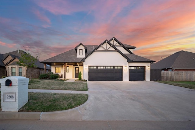 view of front of house featuring concrete driveway, a lawn, fence, a garage, and stucco siding