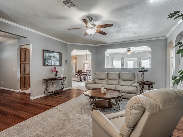 living area with arched walkways, wood finished floors, visible vents, and ceiling fan with notable chandelier