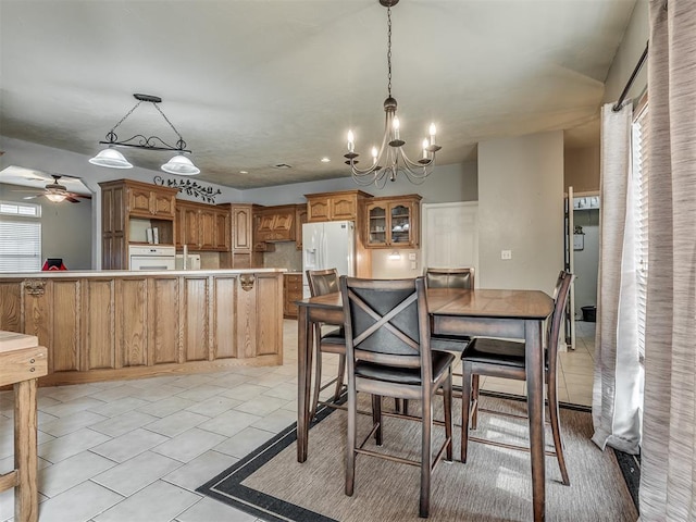 dining space with light tile patterned floors and ceiling fan with notable chandelier