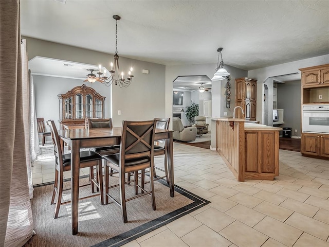 dining room with ceiling fan with notable chandelier, arched walkways, and light tile patterned floors