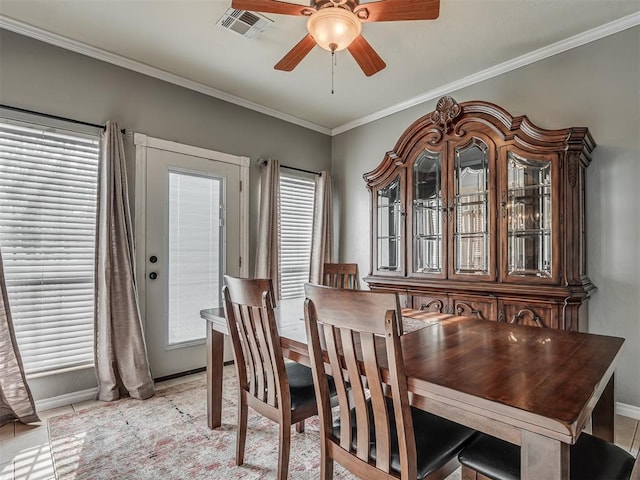 dining room featuring visible vents, crown molding, baseboards, and a ceiling fan