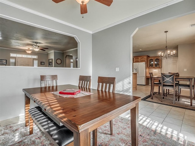 dining area featuring arched walkways, light tile patterned floors, ornamental molding, and ceiling fan with notable chandelier