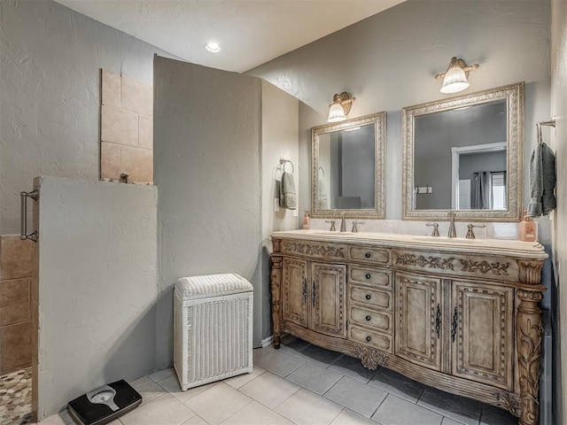 bathroom with double vanity, a textured wall, tile patterned floors, and a sink