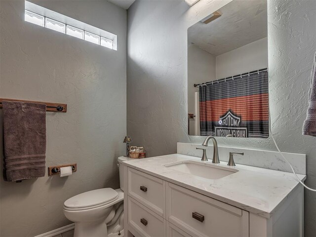 bathroom with a textured wall, vanity, a shower with shower curtain, and toilet