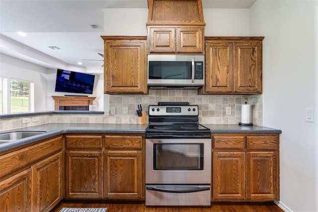 6574 Mint Julep Ln, Guthrie, OK 73044 - kitchen featuring appliances with stainless steel finishes, dark countertops, dark wood-type flooring, backsplash, and brown cabinets