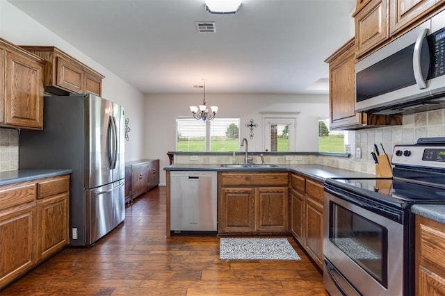6574 Mint Julep Ln, Guthrie, OK 73044 - kitchen featuring stainless steel appliances, a peninsula, brown cabinetry, and dark wood-style floors