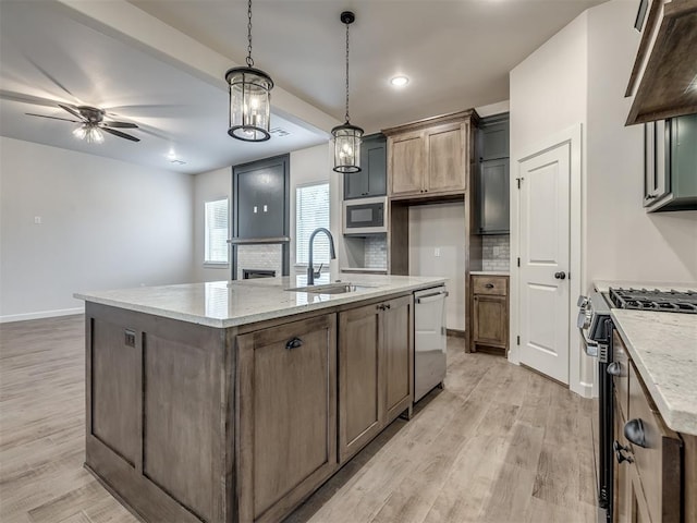 kitchen with ventilation hood, a sink, tasteful backsplash, appliances with stainless steel finishes, and light wood-type flooring