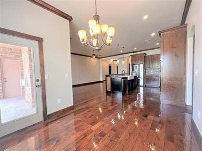 708 Kearny Ln, Yukon, OK 73099 - kitchen with a chandelier, dark wood-style flooring, decorative light fixtures, a kitchen island with sink, and crown molding