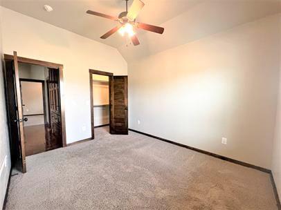708 Kearny Ln, Yukon, OK 73099 - unfurnished bedroom with light carpet, vaulted ceiling, and ceiling fan