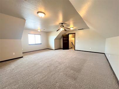 708 Kearny Ln, Yukon, OK 73099 - additional living space with light colored carpet, ceiling fan, and vaulted ceiling