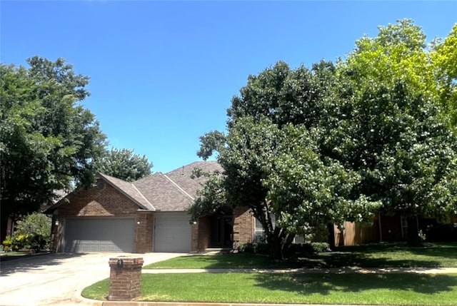 713 NW 143rd St, Edmond, OK 73013 - view of front of home featuring brick siding, an attached garage, concrete driveway, and a front yard