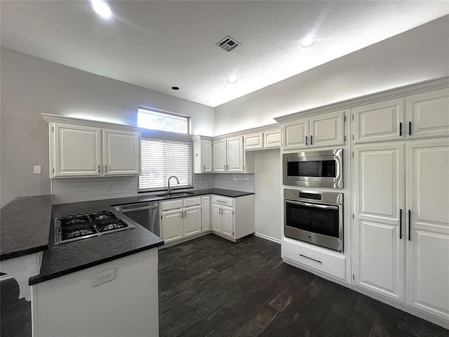 713 NW 143rd St, Edmond, OK 73013 - kitchen featuring stainless steel appliances, dark countertops, tasteful backsplash, dark wood-type flooring, and a peninsula