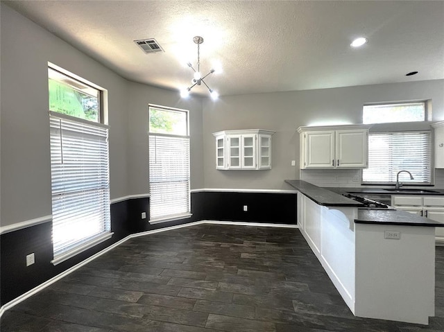 713 NW 143rd St, Edmond, OK 73013 - kitchen featuring a peninsula, dark countertops, white cabinets, a chandelier, and a textured ceiling