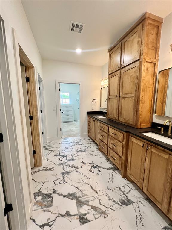 bathroom featuring marble look tile flooring, double vanity, and baseboards